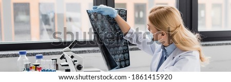 scientist in medical mask looking at x-ray in lab, banner