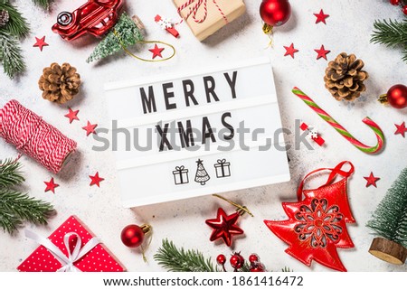Christmas background with fir tree, present box and decorations at white table. Top view image.