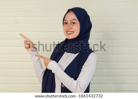Asian muslim hijab woman with hand point on empty space	