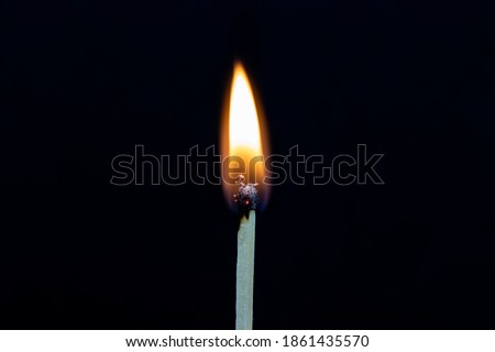 Single matchstick on fire isolated on black background 