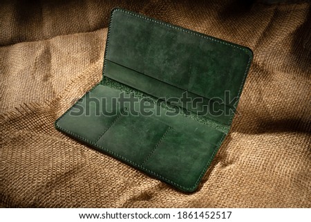 green wallet made of genuine leather on a burlap background close up