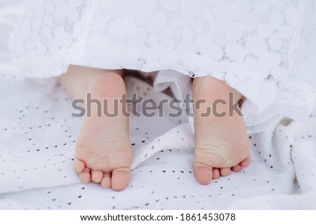 Newborn Baby Feet Covered White Blanket Close-up Photography. Cute Little Child Smooth Legs Heels and Fingers Skin. Attractive Kid Lying in Bed, Comfortable Morning Bedtime at Home