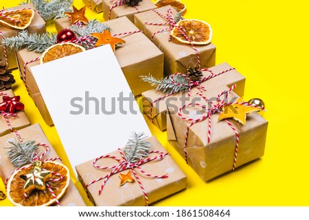 New year postcard mockup with many presents and christmas decor on yellow background. Holiday packaging border with pine tree branch, wrapped paper boxes. Greetings template