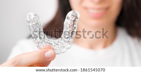 Close up orthodontic transparent aligner in womans hand. Removable braces. Royalty-Free Stock Photo #1861545070