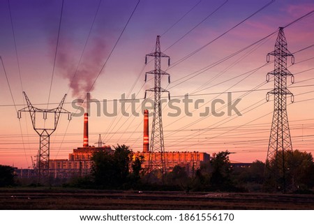 Power station with smoking chimney among electric wires