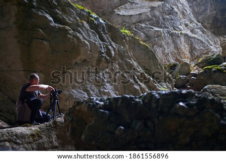 Professional photographer with large backpack, tripod and camera in a cave