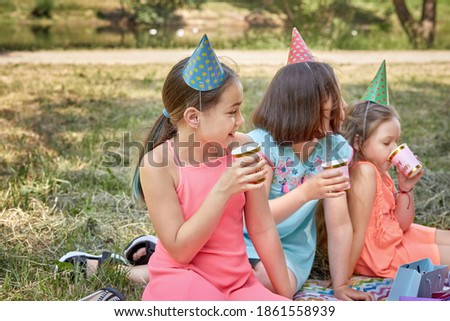 A girl in a party hat with a soda in a Cup celebrates her birthday. In the Park in the summer.