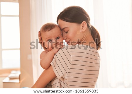 Tender moment. Mother enjoying great time with her lovely baby, while holding him at her hands and bonding with tenderness. Motherhood and happy chidhood concept
