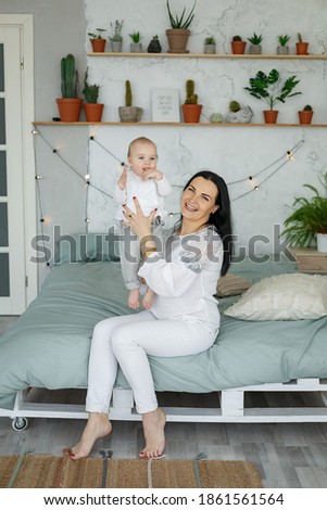 Happy loving family, mother playing with daughter in bedroom on bed. Parent and child relax at home. Concept motherhood and parenting. Interior of bright bedroom in loft style. Family in quarantine