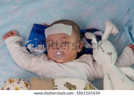 Asian Chinese baby sleeping during high fever with cool fever jel pad on forehead