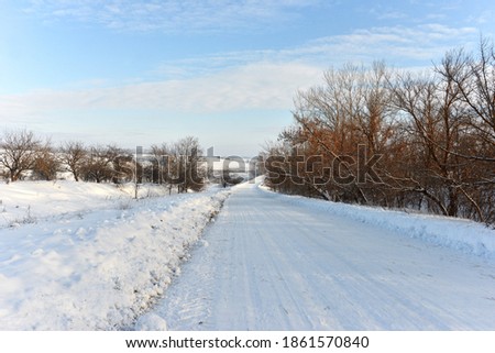 Beautiful snowy winter landscape in the forest. Road and drifts cleaned by the tractor. Weather in frost and cold