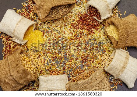Assorted variety of cereals in handmade sacks. Mix of indispensable ingredients for a healthy diet. Black stone concrete background, top view