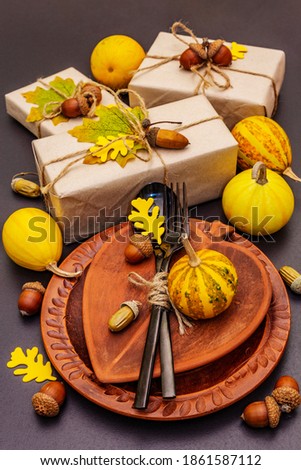 Autumn table setting. Thanksgiving or Halloween concept. Crafted gift boxes, fall decor and black cutlery. Stone concrete background, close up