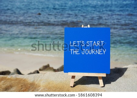 Blue notice board with inspiration quote on sandy beach background.         