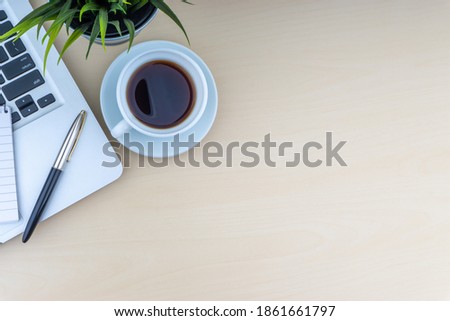 Laptop, notepad, fountain pen, decorative plant and cup of coffee on wooden background. Business and copy space concept.
