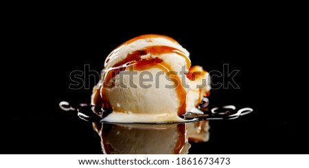 Ice cream ball with a caramel topping on a black background