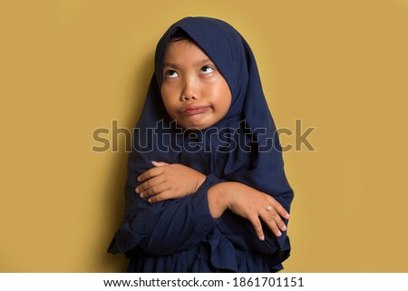 asian little muslim girl wearing hijab with weird expression	