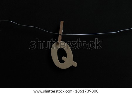 The alphabet 'Q' hangs on the iron wire