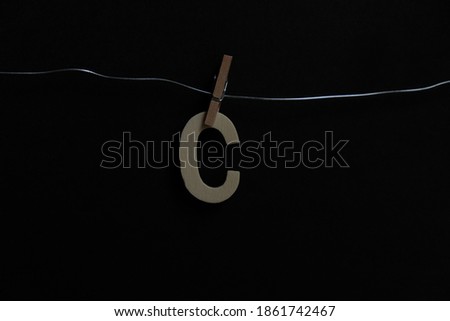 The alphabet 'C' hangs on the iron wire