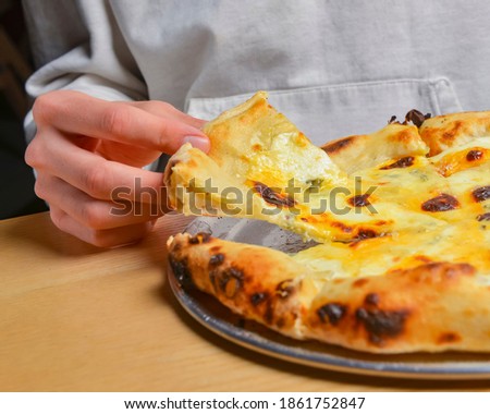 Young man eating a slice of pizza margherita. Still life, eating out concept. At restaurant or at home, pizza delivery, close up on pizza.