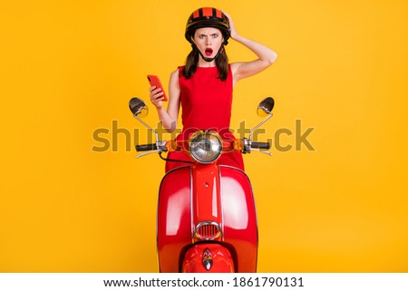Photo of excited angry woman dressed red outfit helmet riding vintage moped holding arm device isolated yellow color background