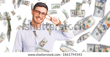 Handsome young man with bear wearing elegant business shirt and glasses doing peace symbol with fingers over face, smiling cheerful showing victory