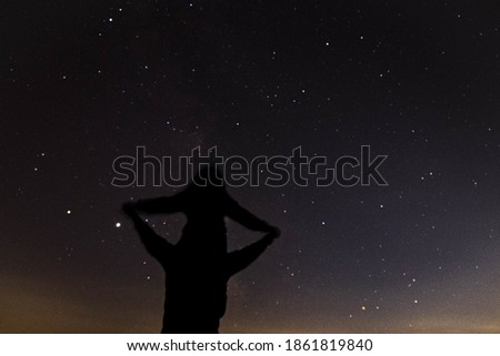 A silhouette of a father giving a shoulder ride to his daughter with a glowing bright starry sky behind