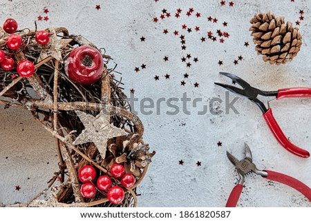 Christmas Wreath Made of branches decorated with gold wooden stars and red berry bubbles. Creative diy craft hobby. Making handmade christmas decorations. Top view class with metal pliers, nippers