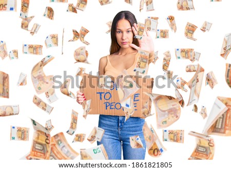 Beautiful brunette young woman holding power to the people banner with open hand doing stop sign with serious and confident expression, defense gesture