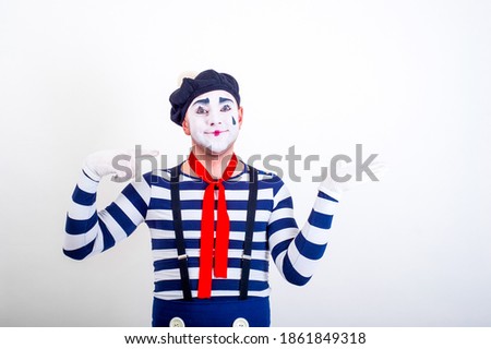 A MIME with a cheerful face shows his hands to the right. A funny clown on a white background shows the direction with his hands. Emotions. Banner, advertising.