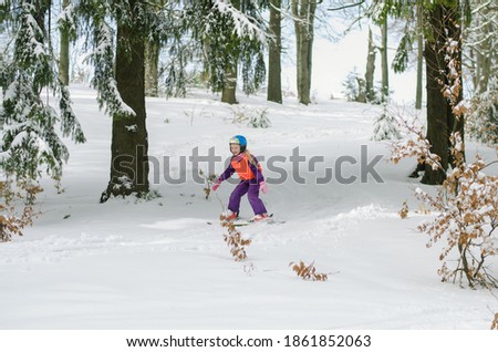 little child skiing in winter slope among trees