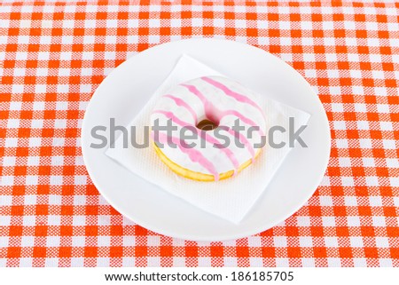Tasty doughnut covered with sugar strawberry glaze  on plate