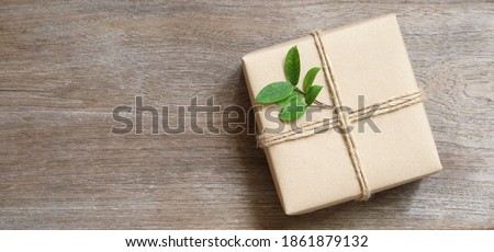 gift box wrapped in recycled paper with rope and leaf on wood background with copy space for text or image , green concept
