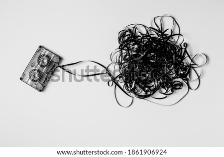 Old cassette with unwound tape isolated on white background. Black and white photography. Royalty-Free Stock Photo #1861906924