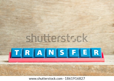 Tile letter on red rack in word transfer on wood background
