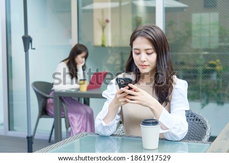 Asian woman using the smartphone at the sidewalk cafe