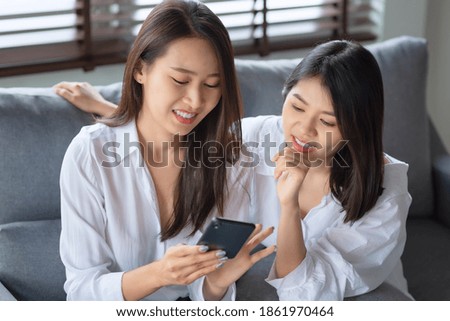 Two asian woman enjoy watching photo on mobile phone at home