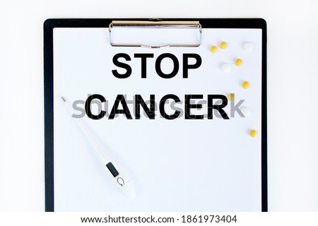 On the tablet for writing the text STOP CANCER, next to the thermometer and yellow tablets.