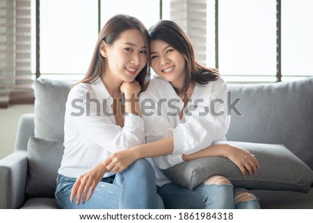 Two asian females take a portrait photo with charming smile in living room at home