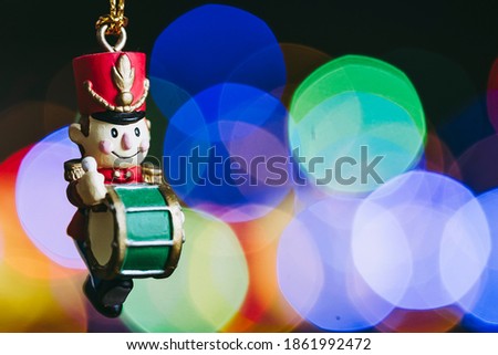 Christmas decoration in the shape of a soldier with a tambourine on a colorful blurry lights background - Christmas decor and bokeh colored light spots