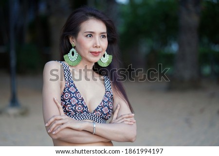Beautiful woman in black bikini standing outdoors at beach, leisure activities.