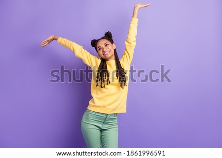 Photo of optimistic nice lady hands up wear yellow sweater trousers look empty space isolated on lilac color background