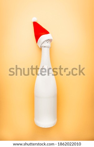 White Champagne bottle on light orange background. Flat lay, top view, trendy christmas concept.