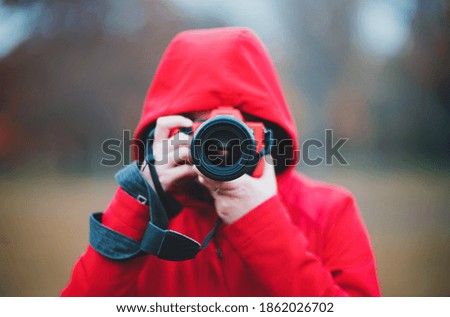 Photographer in center taking photo with lens and red hoodie rainy autumn day