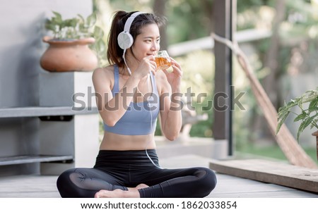 Asian beautiful and sportive woman drinking hot tea and wearing headphone while doing meditation in garden at morning time. Healthy Concept. Royalty-Free Stock Photo #1862033854