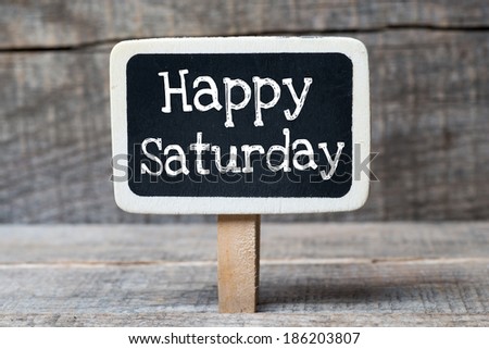 Small wooden framed blackboard on wooden background with text Happy Saturday
