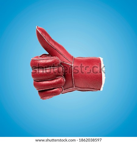 Gesturing red leather glove on blue background. Minimal art fashion concept.