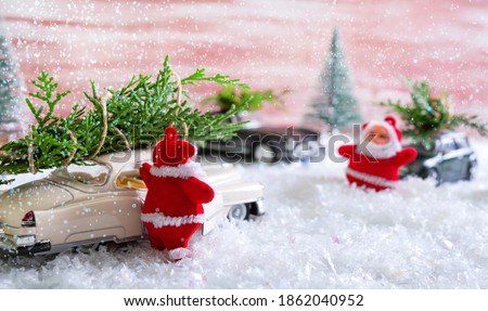 Toy Santas met in the forest, standing near the cars that deliver Christmas trees. Magic atmosphere. Christmas celebration concept, for postcards.