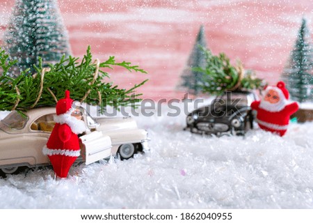 Toy Santas met in the forest, standing near the cars that deliver Christmas trees. Magic atmosphere. Christmas celebration concept, for postcards. 