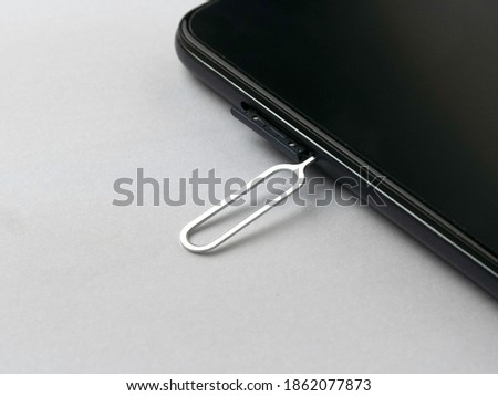 Sim card tray remover eject pin key tool and smartphone. Royalty-Free Stock Photo #1862077873